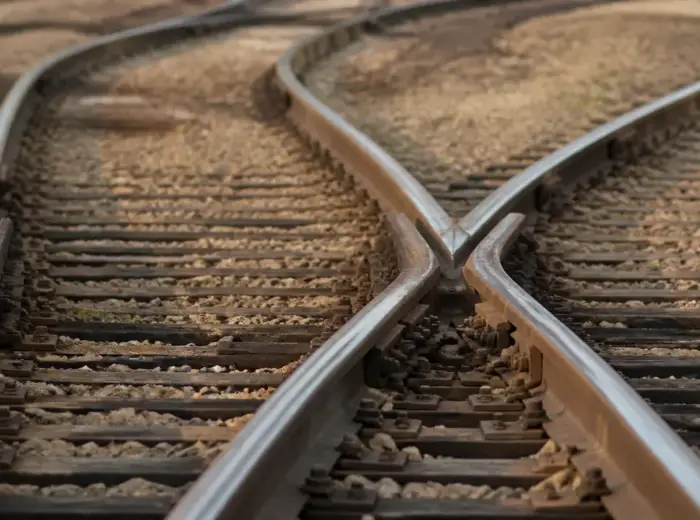 Gros plan d’un aiguillage ferroviaire où les rails divergent nettement vers deux voies distinctes