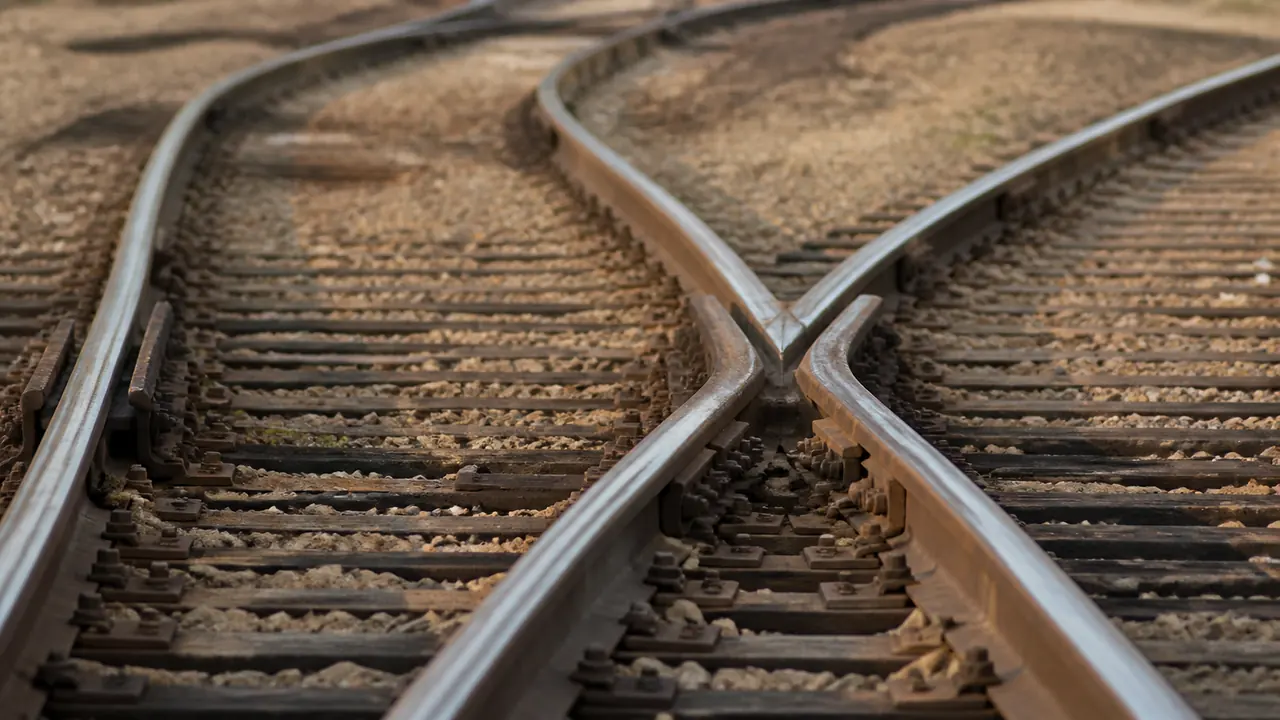 Gros plan d’un aiguillage ferroviaire où les rails divergent nettement vers deux voies distinctes